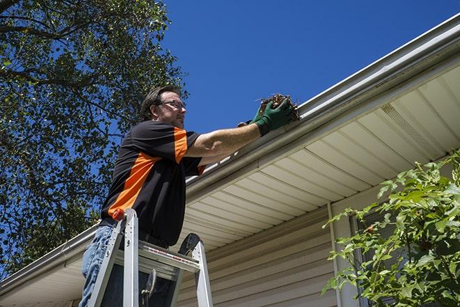 a repair technician inspecting a damaged gutter for necessary repairs in Adrian, MO